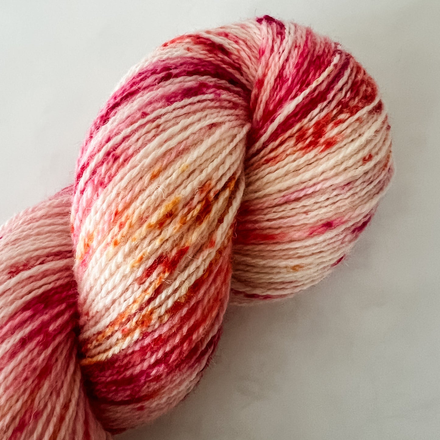 Hand Dyed Fjord Fibres yarn with pink and beige colors on a white background
