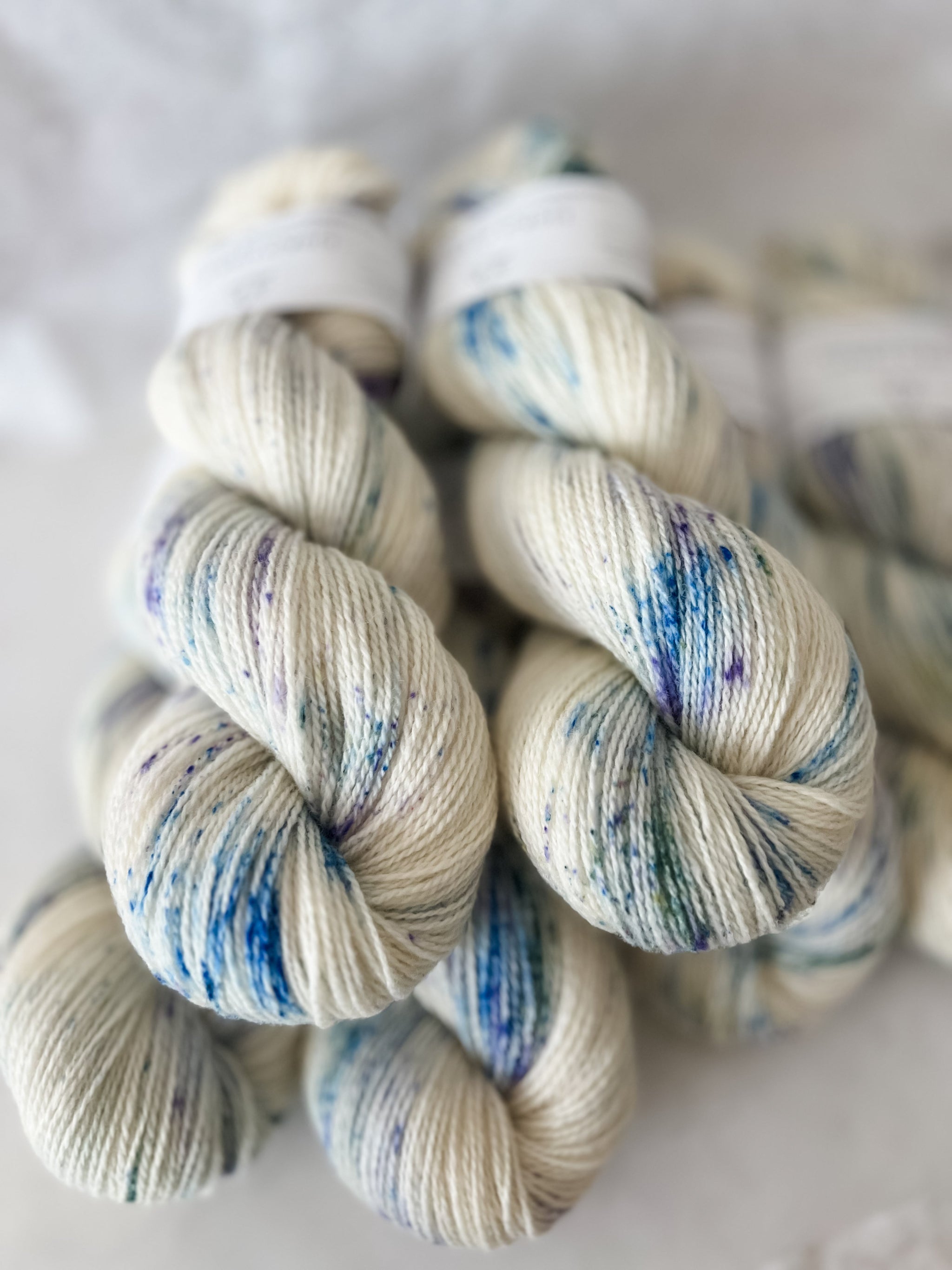 White Hand dyed Fjord Fibres yarn with blue and green speckles on a white background